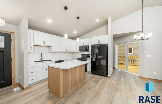 kitchen with sink, a kitchen island, vaulted ceiling, white cabinets, and black appliances