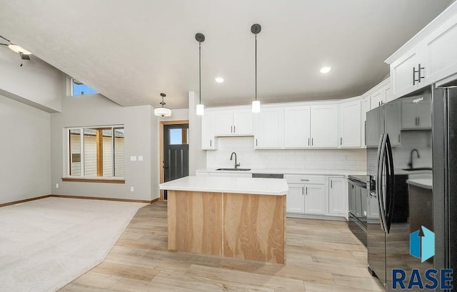 kitchen featuring pendant lighting, a center island, backsplash, white cabinets, and light hardwood / wood-style flooring