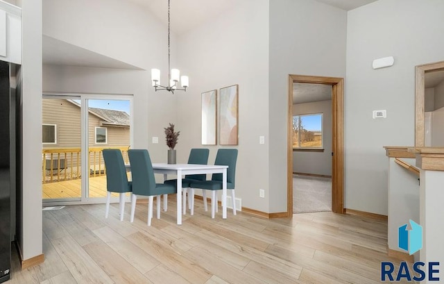 dining space featuring light wood-type flooring, a wealth of natural light, and a towering ceiling