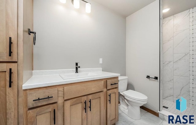 bathroom featuring a tile shower, vanity, and toilet