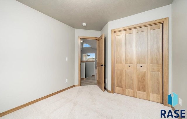 bedroom with a textured ceiling, light carpet, and a closet