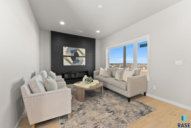 living room with a large fireplace and light hardwood / wood-style floors