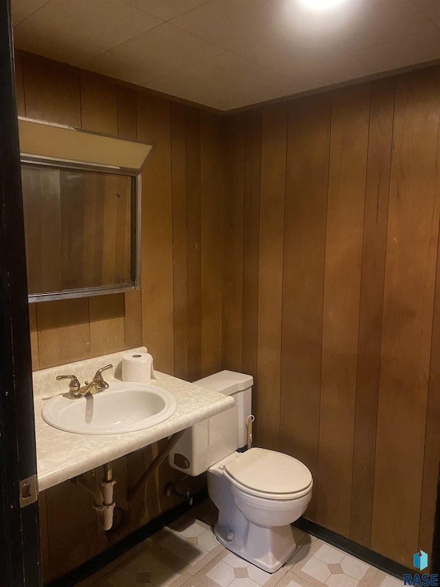 bathroom featuring wood walls, sink, and toilet