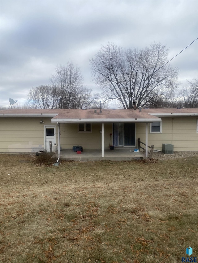 rear view of property featuring a patio, a lawn, and central air condition unit