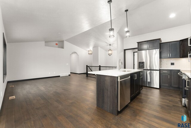 kitchen with sink, dark wood-type flooring, an island with sink, decorative light fixtures, and appliances with stainless steel finishes