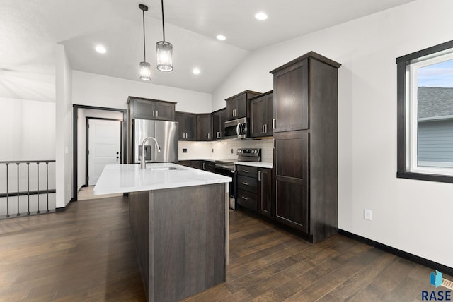 kitchen with lofted ceiling, a kitchen island with sink, decorative light fixtures, dark hardwood / wood-style flooring, and stainless steel appliances