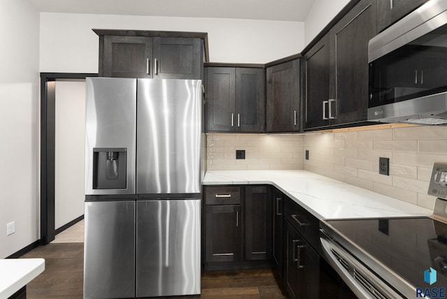 kitchen featuring light stone countertops, appliances with stainless steel finishes, backsplash, dark brown cabinetry, and dark hardwood / wood-style floors