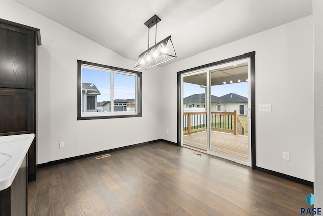 unfurnished dining area featuring dark hardwood / wood-style floors and lofted ceiling