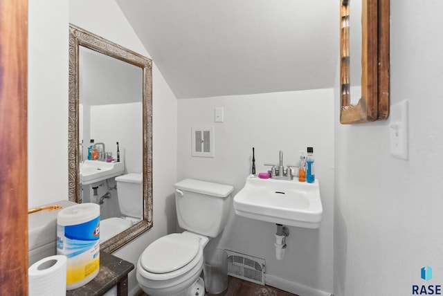 bathroom with toilet, hardwood / wood-style flooring, vaulted ceiling, and sink