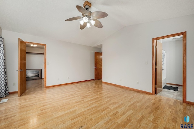 spare room featuring a textured ceiling, light wood-type flooring, ceiling fan, and lofted ceiling