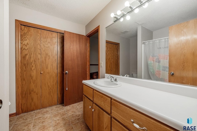 bathroom featuring vanity, a textured ceiling, toilet, and tile patterned flooring