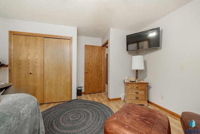 bedroom with a textured ceiling, light wood-type flooring, and a closet