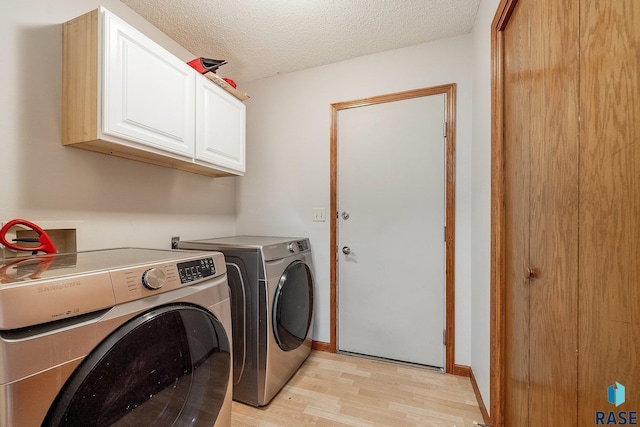 clothes washing area with cabinets, a textured ceiling, light wood-type flooring, and washing machine and clothes dryer