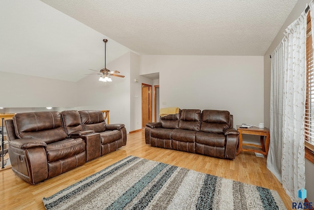 living room featuring hardwood / wood-style floors, ceiling fan, lofted ceiling, and a textured ceiling