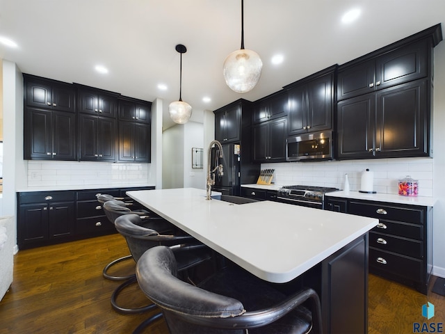 kitchen with backsplash, an island with sink, and stainless steel appliances