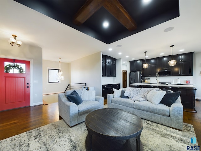 living room with beamed ceiling, a notable chandelier, dark hardwood / wood-style flooring, and sink