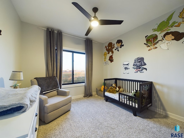 bedroom featuring ceiling fan, light carpet, and a nursery area