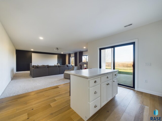 kitchen with white cabinets, a center island, and light hardwood / wood-style floors