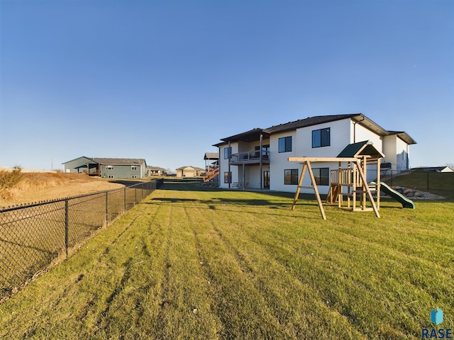 back of property featuring a playground and a lawn