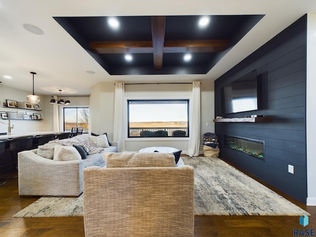 cinema featuring beam ceiling, dark hardwood / wood-style flooring, a fireplace, and a chandelier