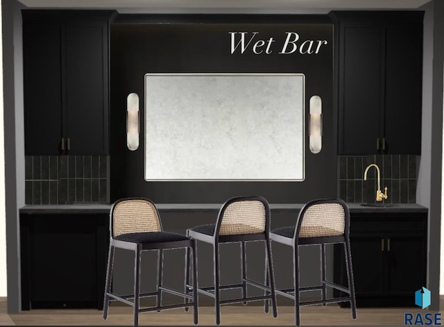 bar with decorative backsplash, sink, and light hardwood / wood-style flooring