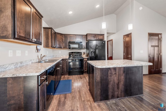 kitchen with dark wood-type flooring, black appliances, sink, hanging light fixtures, and a kitchen island