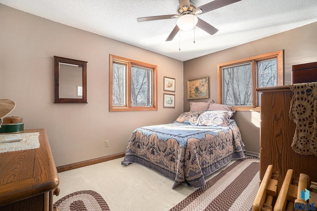 carpeted bedroom featuring ceiling fan and a textured ceiling