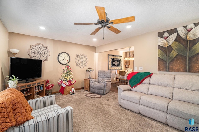 carpeted living room featuring ceiling fan with notable chandelier and a textured ceiling