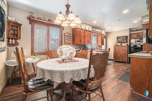 dining space with dark hardwood / wood-style floors and an inviting chandelier