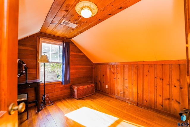 bonus room with hardwood / wood-style flooring, lofted ceiling, and wooden walls