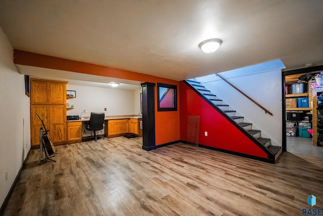 basement with light hardwood / wood-style floors and built in desk