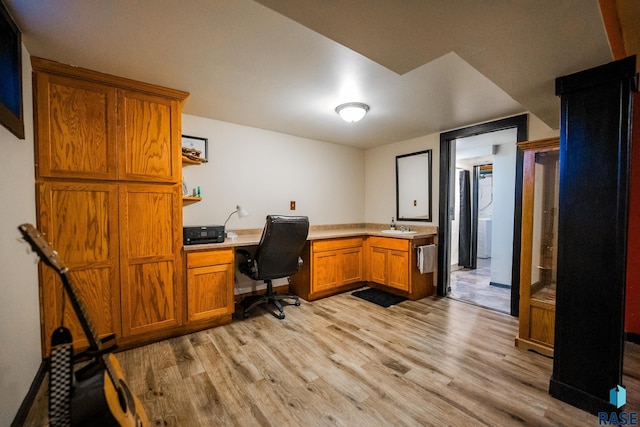 office area featuring built in desk, sink, and light hardwood / wood-style flooring