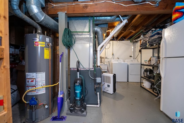 basement featuring washing machine and dryer, white fridge, and gas water heater