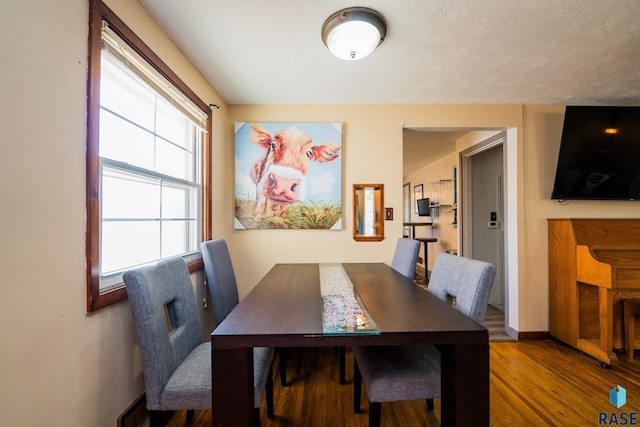 dining area with hardwood / wood-style floors and a textured ceiling