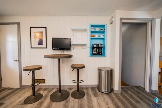 interior space featuring hardwood / wood-style floors, a textured ceiling, a breakfast bar area, and wood walls