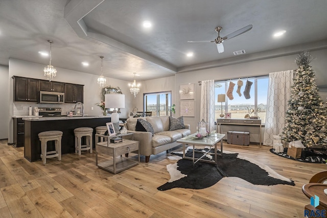 living room featuring ceiling fan, sink, and light wood-type flooring