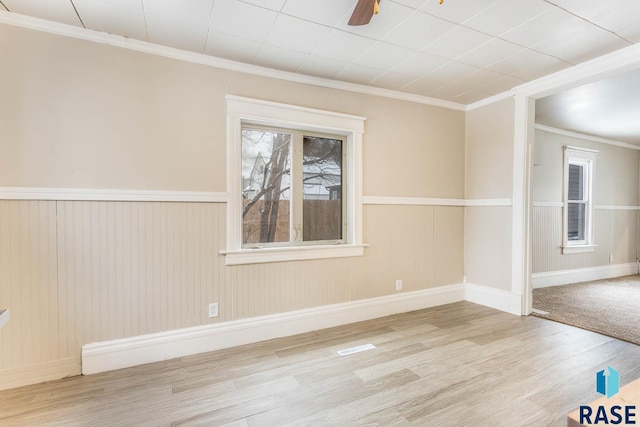 empty room with ceiling fan, light hardwood / wood-style floors, and crown molding