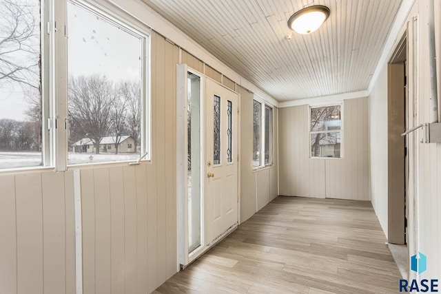 doorway to outside featuring wood walls, crown molding, and light hardwood / wood-style floors