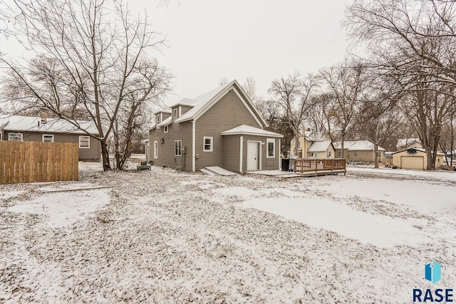 snow covered back of property with a wooden deck