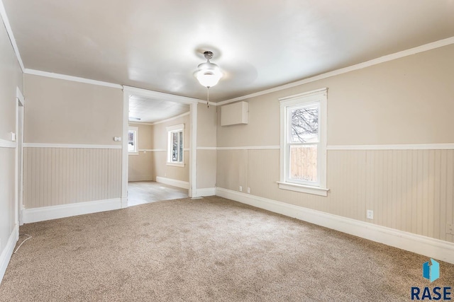 empty room with ceiling fan, light colored carpet, and ornamental molding