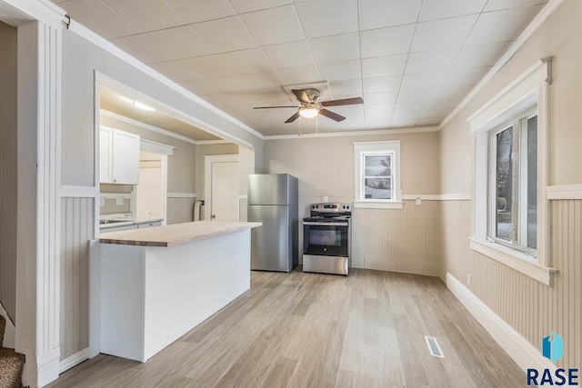 kitchen with butcher block counters, white cabinets, stainless steel appliances, and ornamental molding