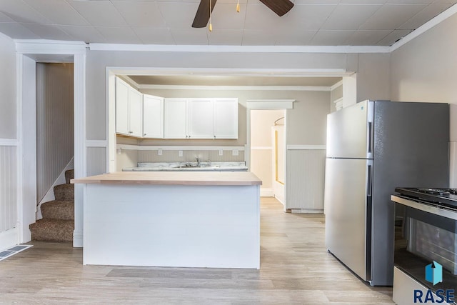 kitchen featuring ceiling fan, white gas stove, light hardwood / wood-style floors, white cabinets, and ornamental molding