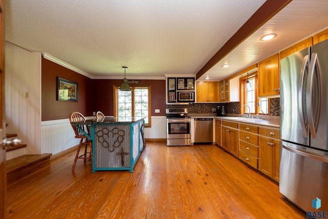 kitchen with pendant lighting, sink, a breakfast bar area, light hardwood / wood-style floors, and stainless steel appliances