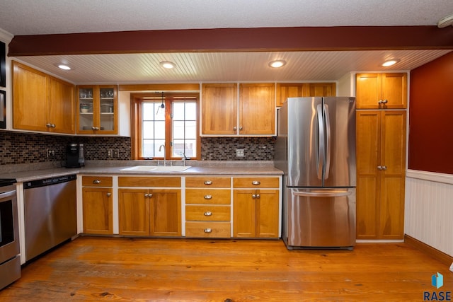 kitchen with sink, stainless steel appliances, tasteful backsplash, beamed ceiling, and light hardwood / wood-style floors