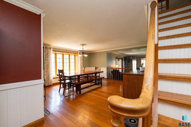 dining room with hardwood / wood-style floors, a textured ceiling, crown molding, and a chandelier