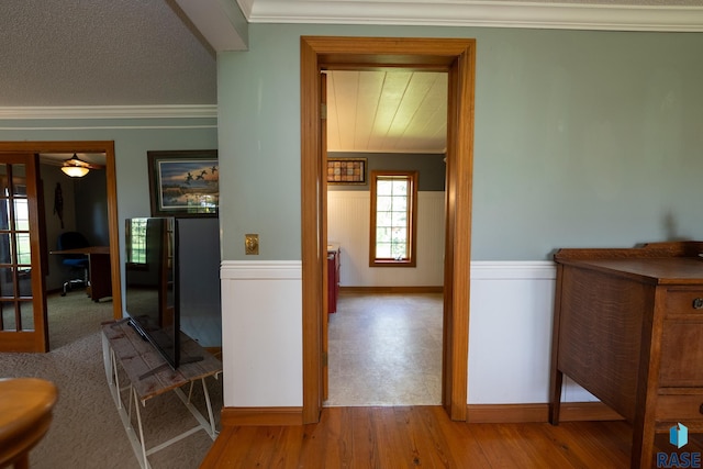 hallway with a textured ceiling, crown molding, and light hardwood / wood-style flooring