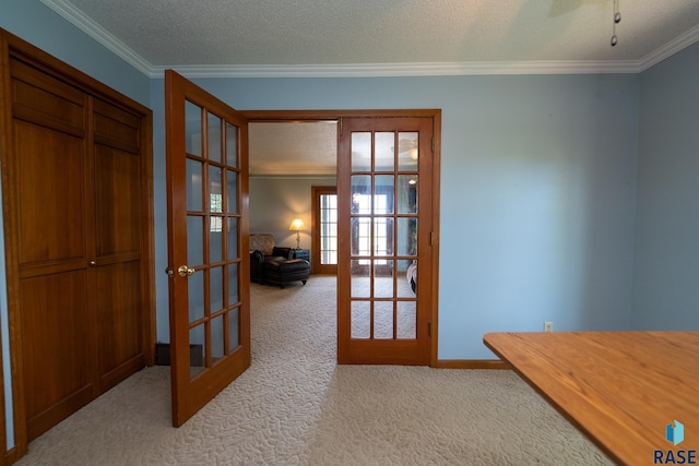 interior space featuring crown molding, light colored carpet, a textured ceiling, and french doors