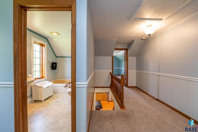 hall with a textured ceiling and lofted ceiling