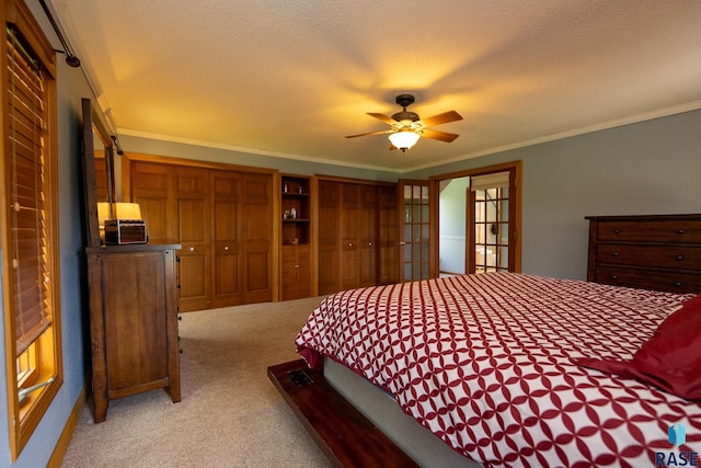 bedroom with light carpet, french doors, a textured ceiling, ceiling fan, and multiple closets