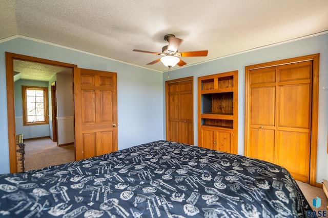 bedroom with a textured ceiling, ceiling fan, lofted ceiling, carpet floors, and multiple closets